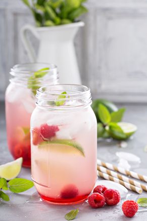 two mason jars filled with raspberry lemonade, mint and lime juice next to strawberries