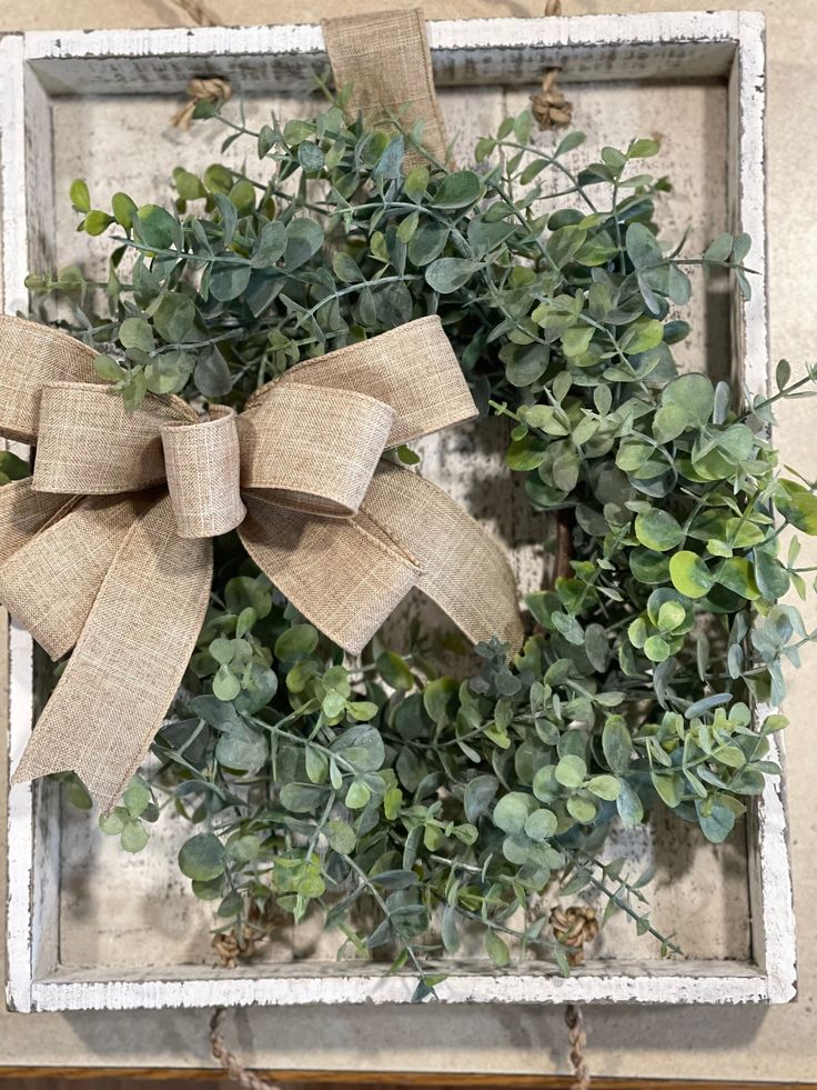 a box with a bow on top of it and some plants in the bottom right corner