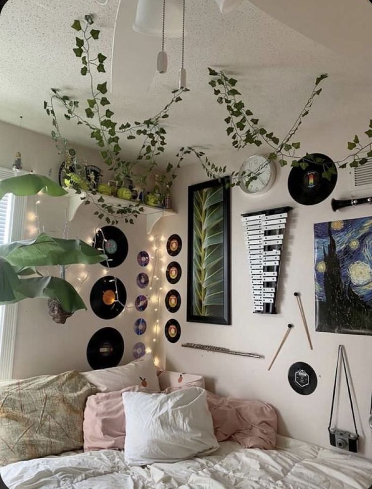 a bedroom with lots of plants hanging from the ceiling and pictures on the wall above it