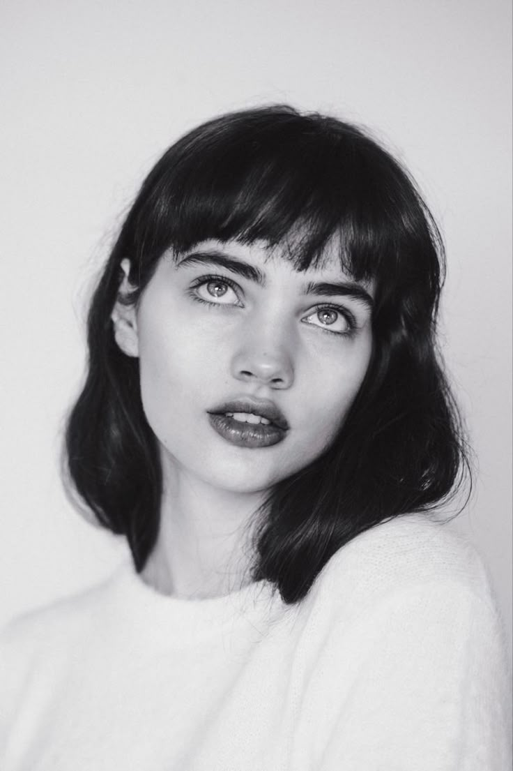 a black and white photo of a woman with dark lipstick on her lips looking at the camera