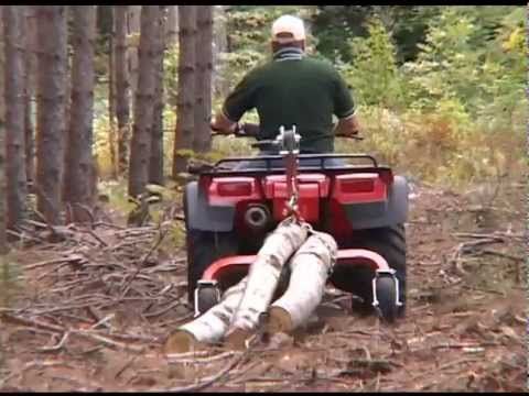 a man riding on the back of a red four - wheeler through a forest filled with trees