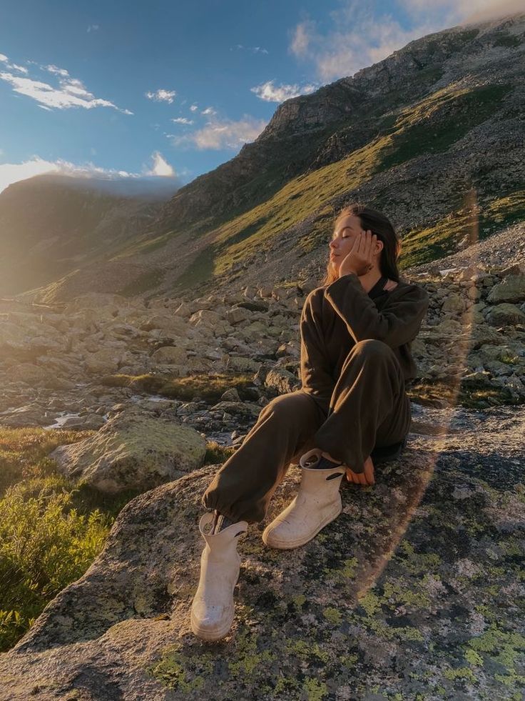 a woman sitting on top of a rocky hillside