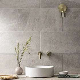 a bathroom with a sink, vase and soap dispenser