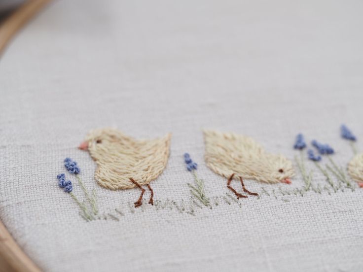 two chickens are walking in the grass with blue flowers