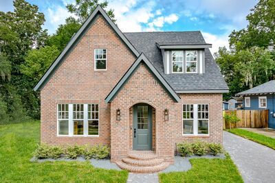 a brick house with white windows and green grass