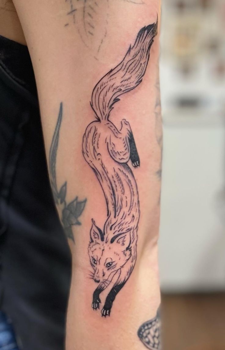 a woman with a tattoo on her arm has a fox and fish design on it