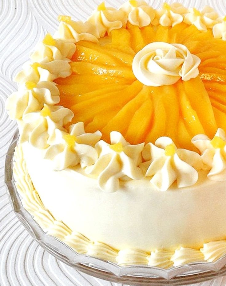 a cake with white frosting and orange slices on it sitting on a glass plate