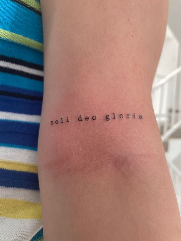 a woman with a small tattoo on her arm that says,'side do glorria