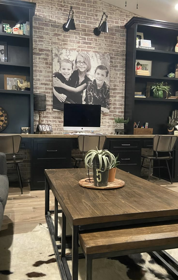 a living room filled with furniture and a brick wall behind the couches in front of a flat screen tv