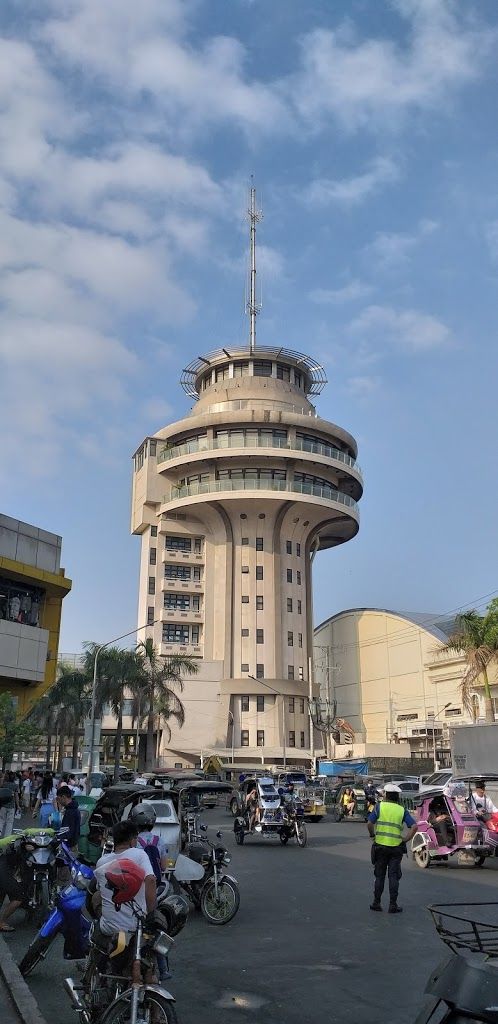 several people on bicycles and cars in front of a tall building with a clock tower