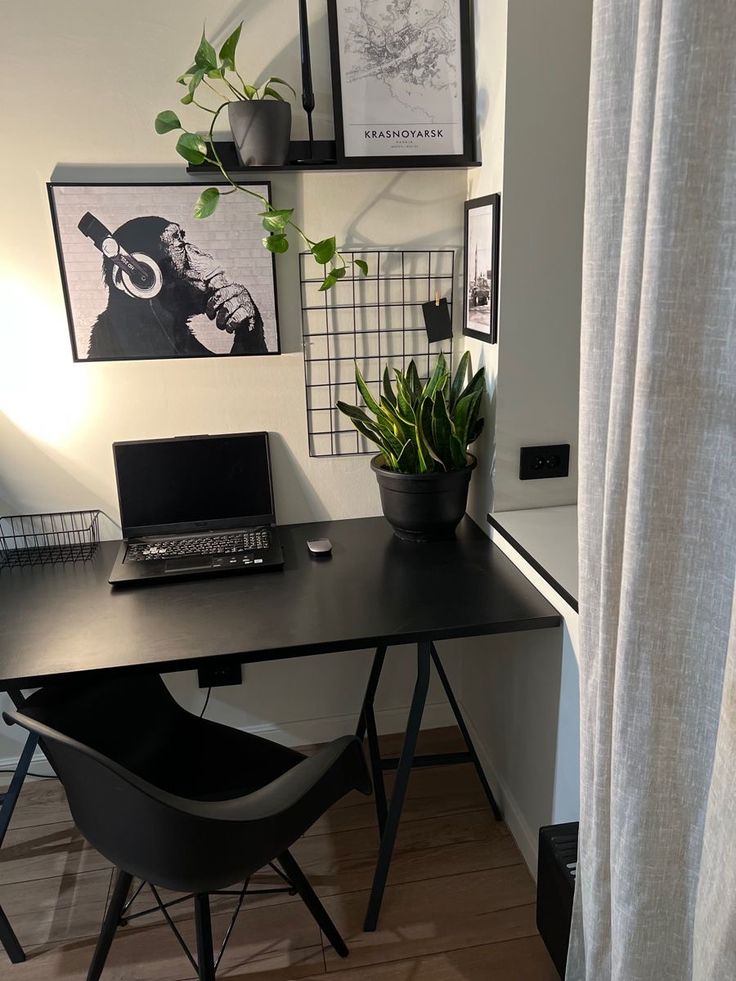 a laptop computer sitting on top of a wooden desk next to a plant in a pot