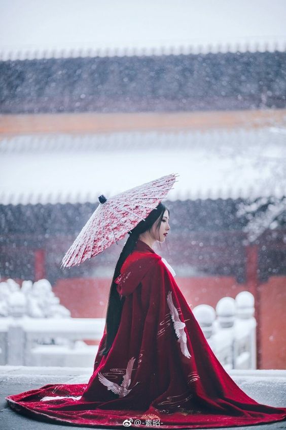 a woman wearing a red kimono and holding an umbrella