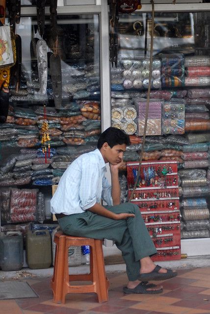 a man sitting on a stool in front of a store