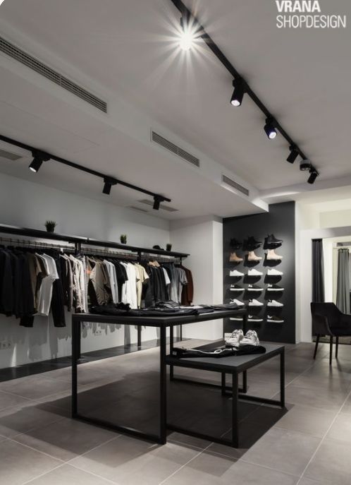 a clothing store with clothes on racks and tables in front of the display area,