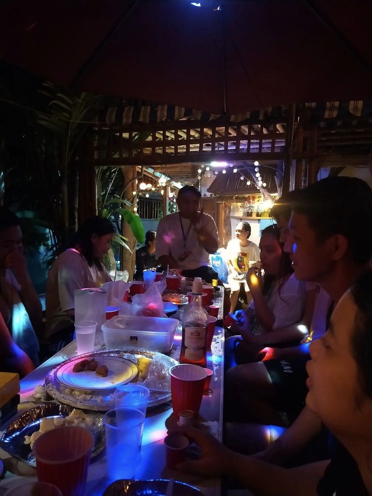 a group of people sitting at a table with food and drinks in front of them