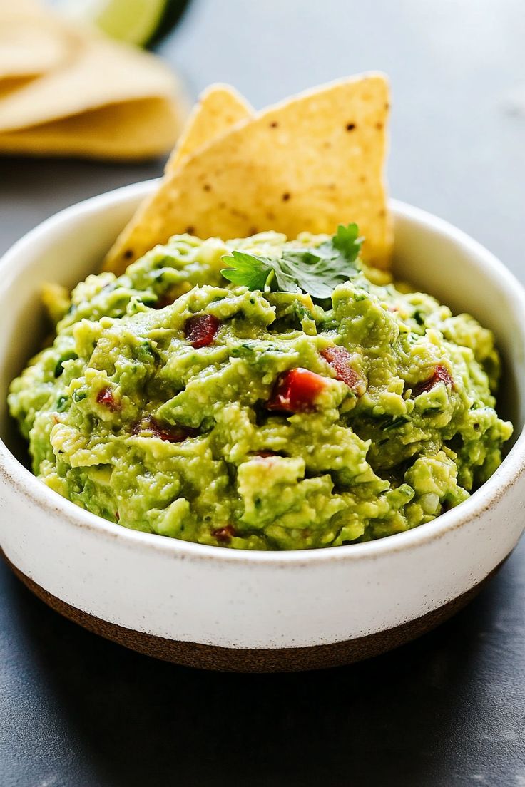 a bowl filled with guacamole and tortilla chips on the side