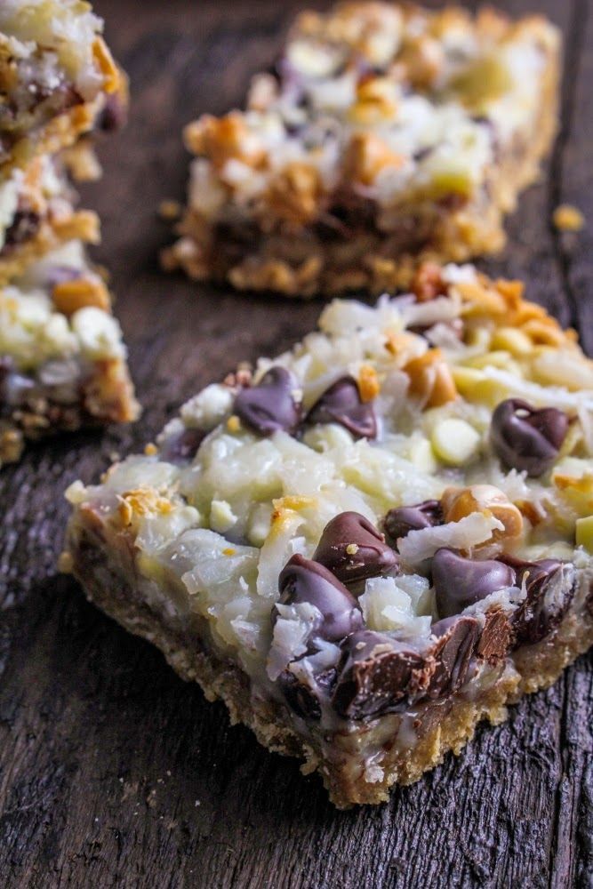 several pieces of chocolate and coconut bars on a wooden table