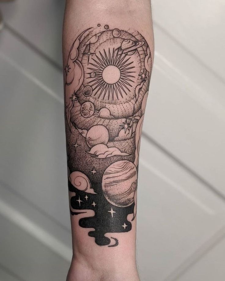 a person's arm with a black and white tattoo design on it, including planets