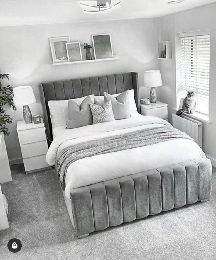 a black and white photo of a bedroom with a bed, nightstands, lamps and pictures on the wall