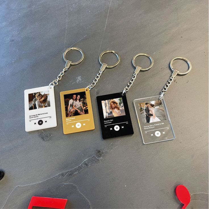 four different key chains with photos attached to them, one being an mp3 player and the other is a camera