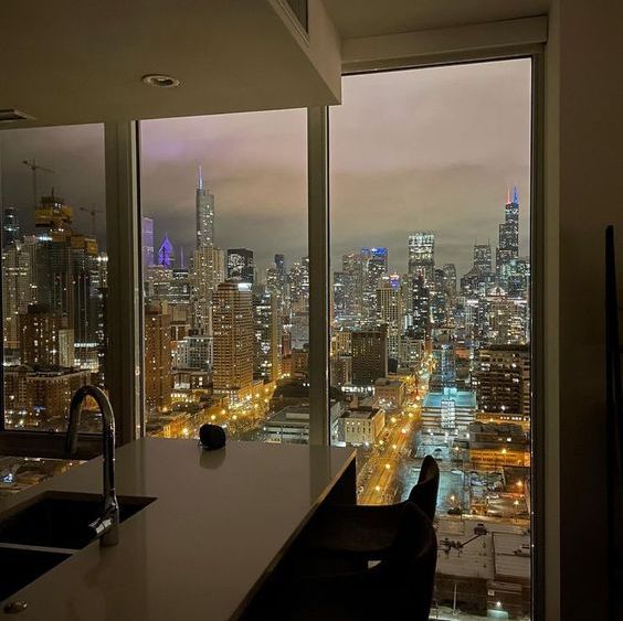 a kitchen with a view of the city at night from it's high rise