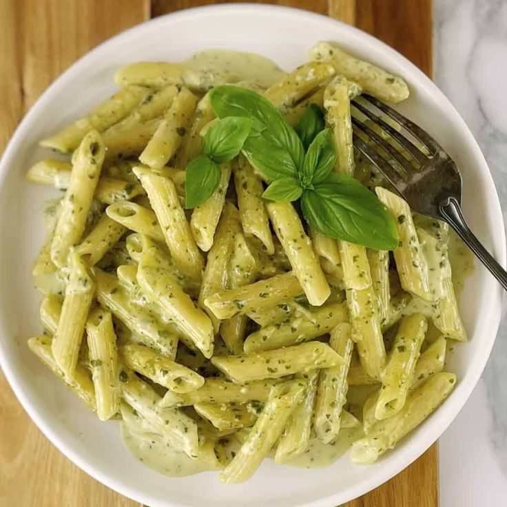 a white bowl filled with pasta and pesto