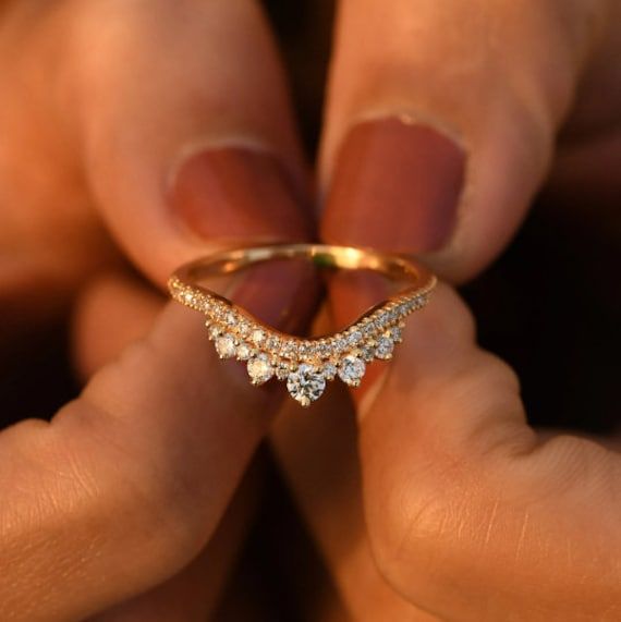 a close up of a person's hand holding a gold ring with diamonds on it