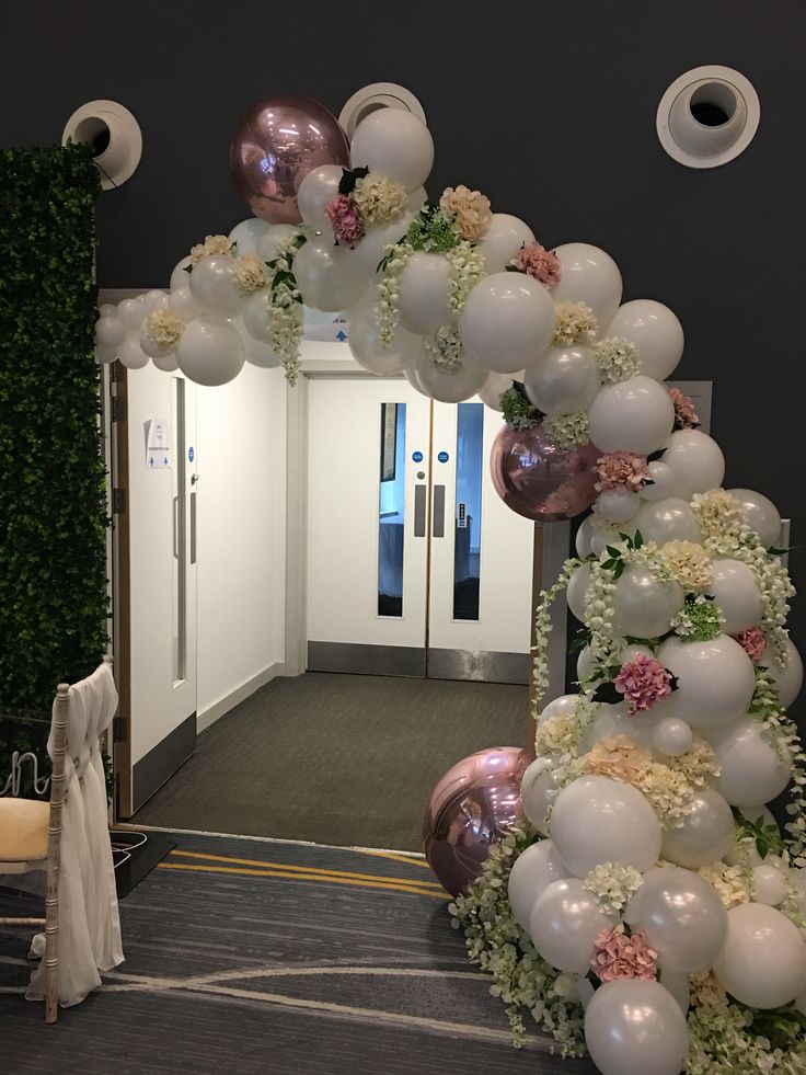 an archway decorated with balloons and flowers for a wedding or special event in the hallway