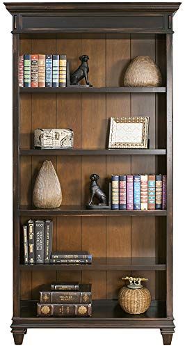 a book shelf with many books on top of it and two vases next to it