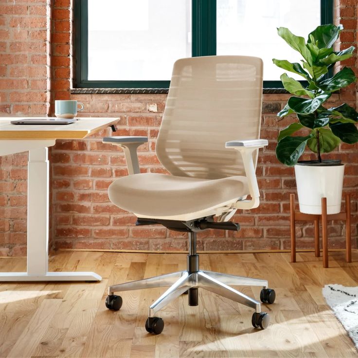 a blue office chair in front of a brick wall with a potted plant next to it