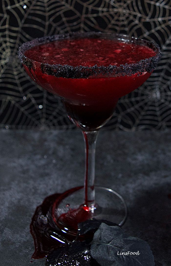 a glass filled with liquid sitting on top of a table next to a spider web net