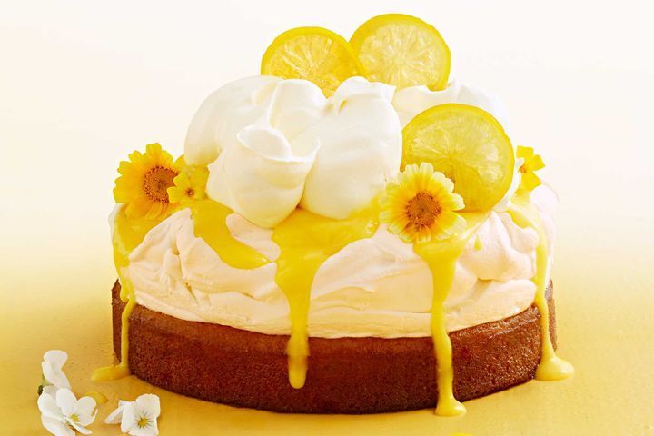 a cake with lemons and whipped cream drizzled on it's sides