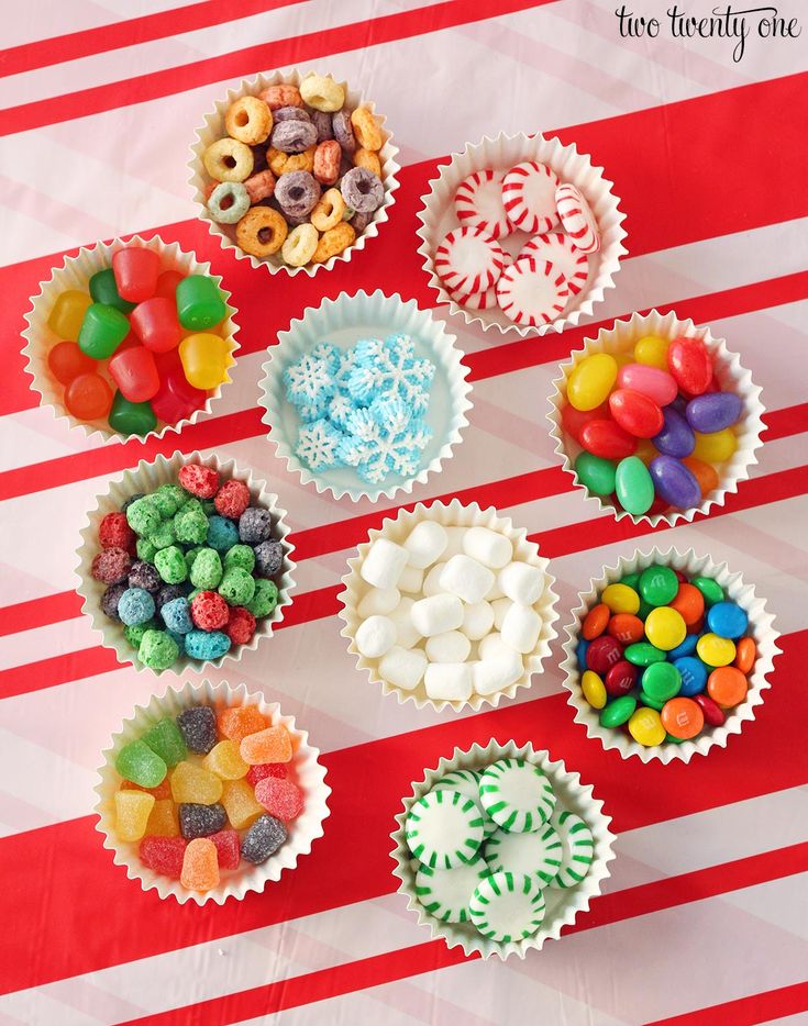 there are many candy cups on the red and white striped tablecloth with candy in them