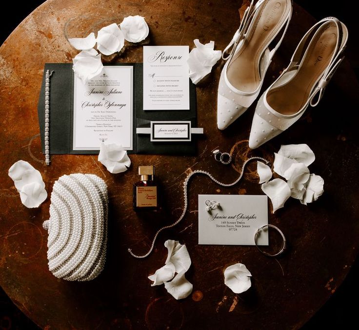 a table topped with white shoes and wedding accessories on top of a wooden table covered in flowers