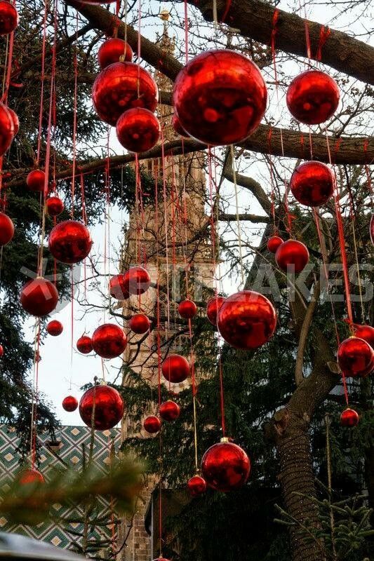 red ornaments hanging from a tree in front of a building