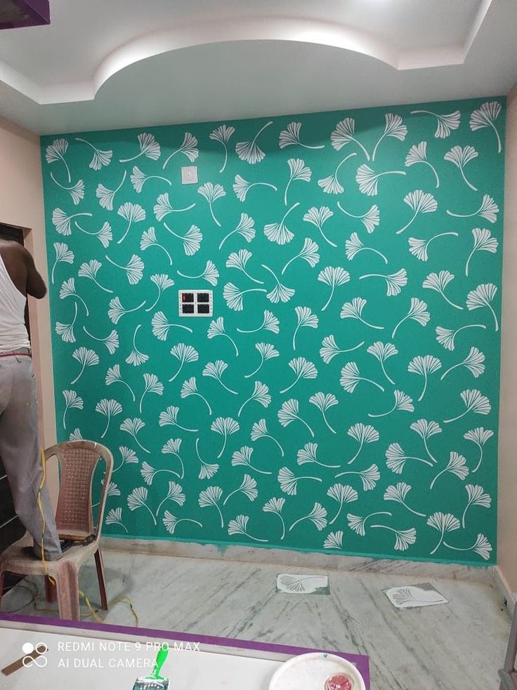 a green wall with white flowers on it in a room that is being renovated and painted