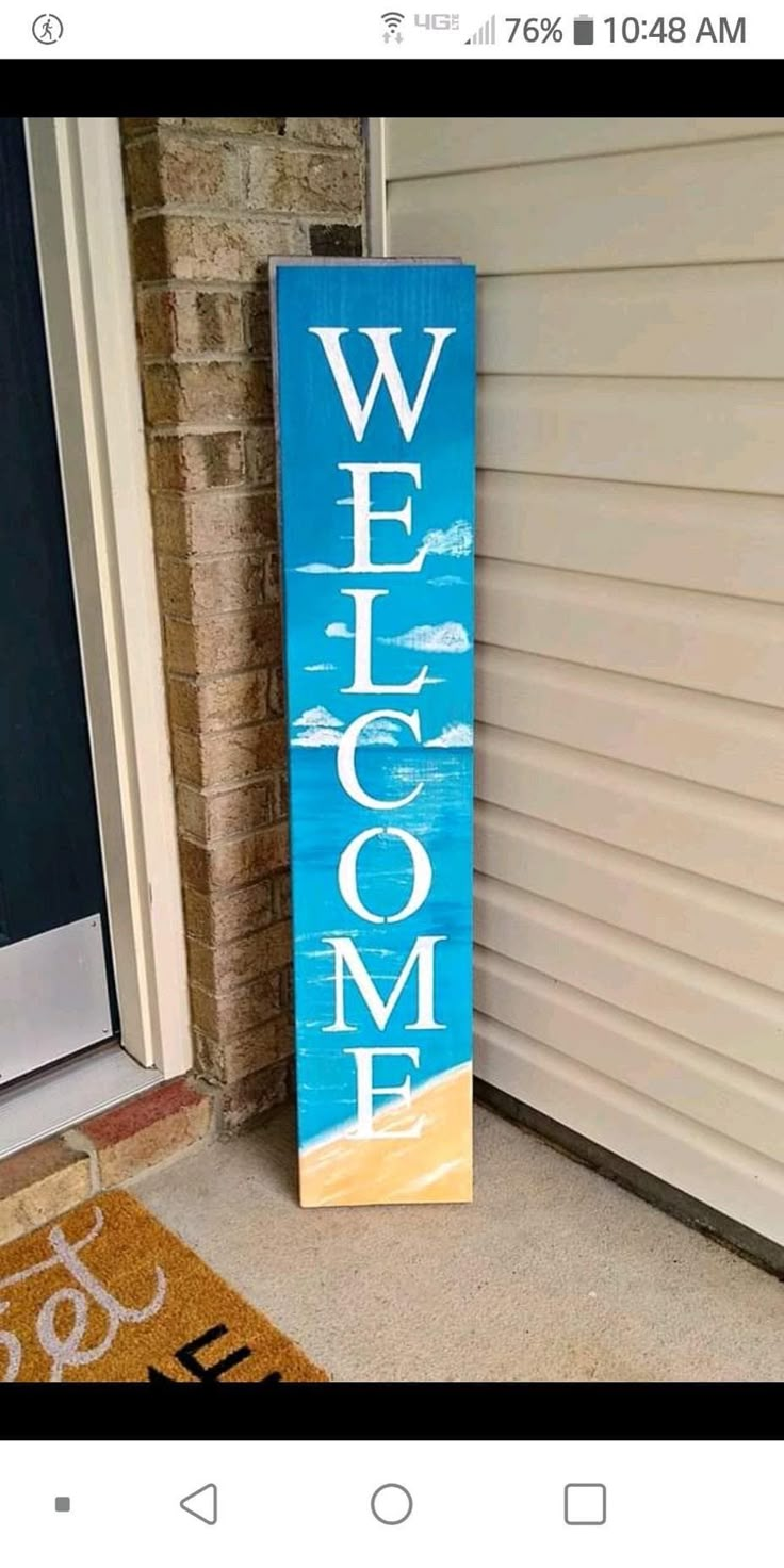 a wooden welcome sign sitting in front of a door with the word welcome painted on it