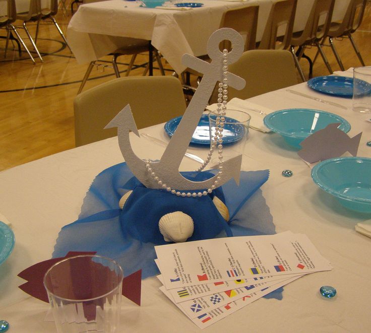 the table is set with blue and white plates, silverware, and an anchor centerpiece