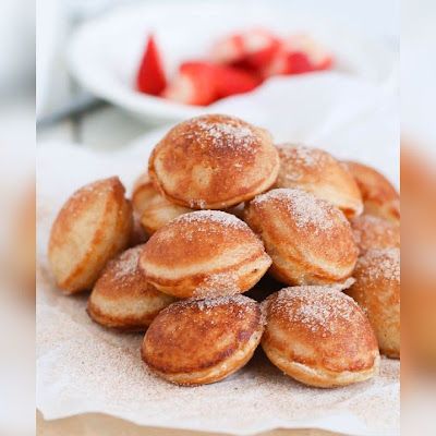 a pile of powdered sugar covered donuts sitting on top of a white plate