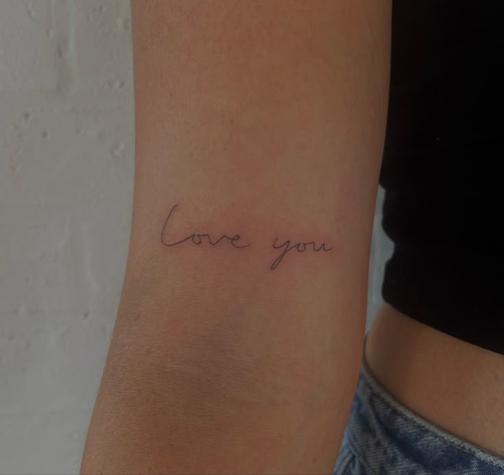 a woman's arm with the word love you written on it, in cursive font