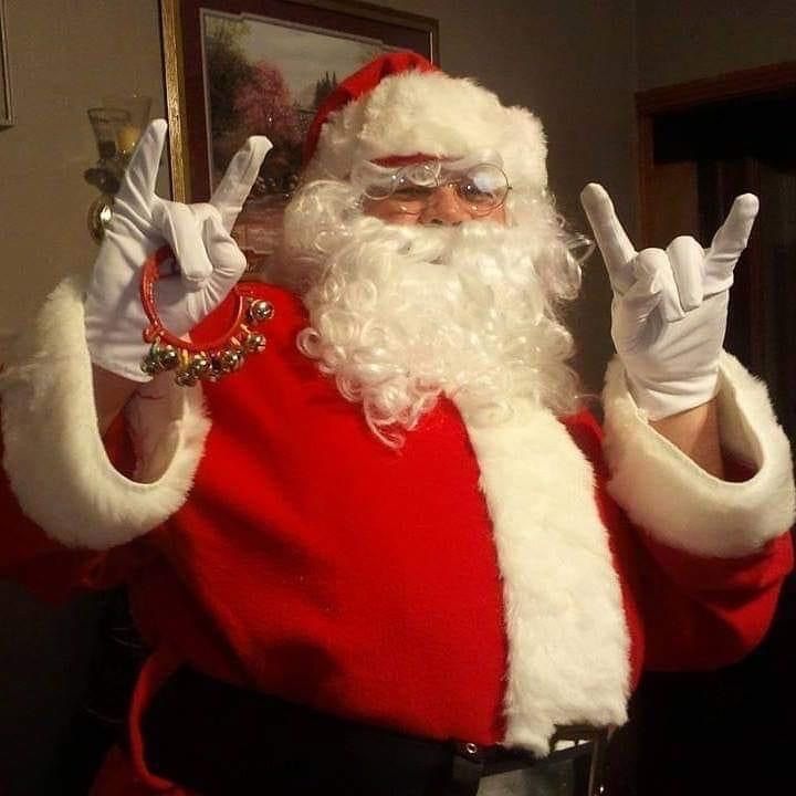 a man dressed as santa claus giving the peace sign with his hands and wearing glasses