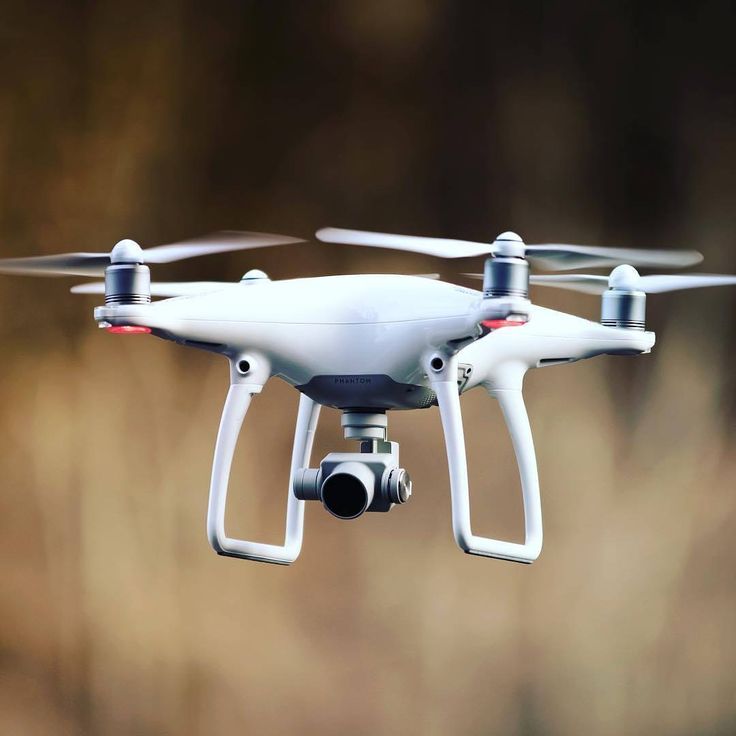 a close up of a white remote controlled aerial device flying in the air with blurry background