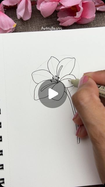 someone is drawing a flower on a piece of paper