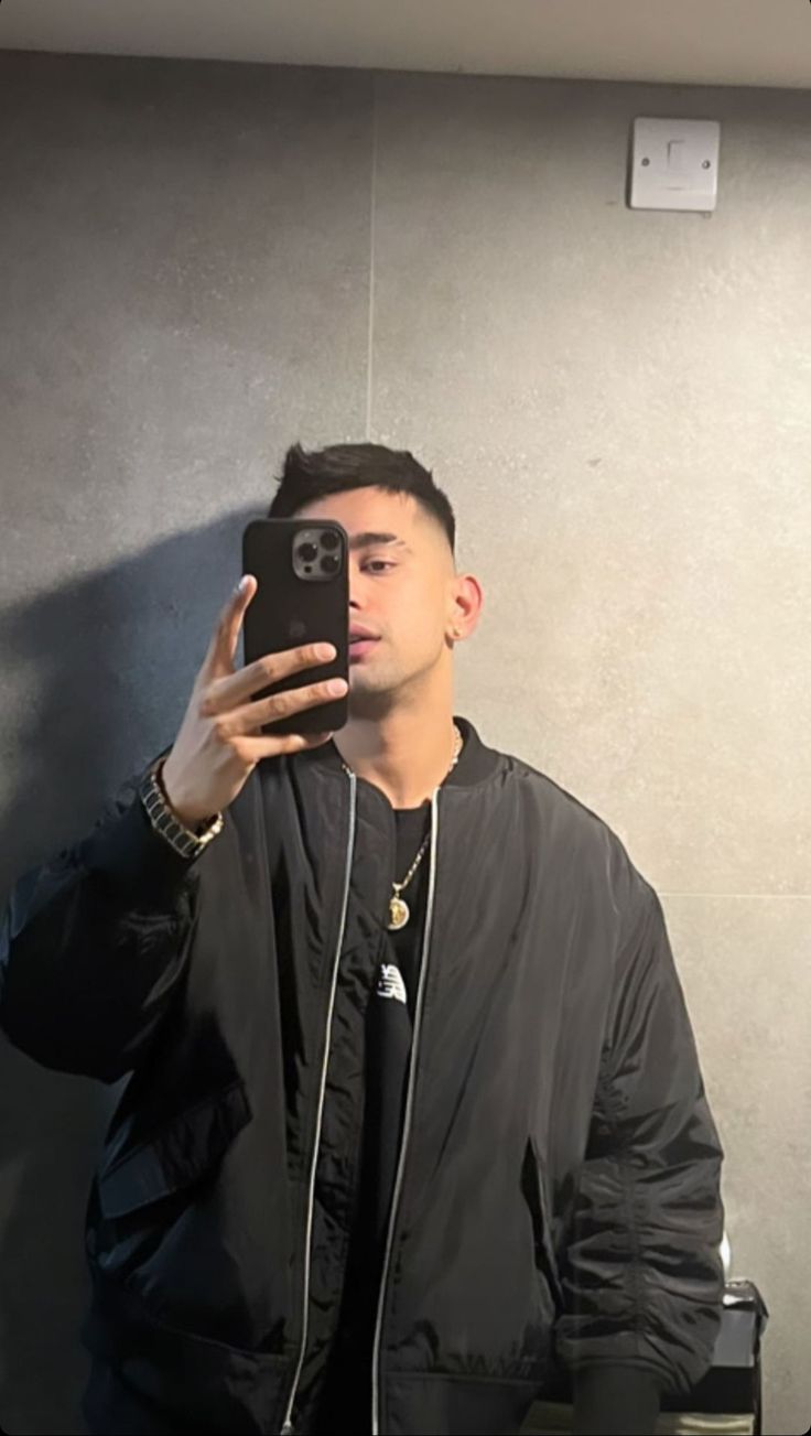 a man taking a selfie in front of a mirror with his cell phone up to his face