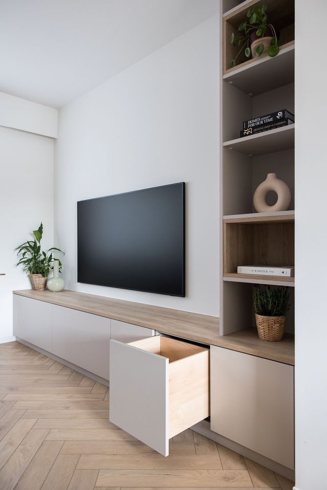 a flat screen tv sitting on top of a wooden shelf next to a white wall