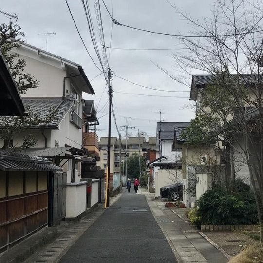 an empty street with houses and power lines in the background on a cloudy day,