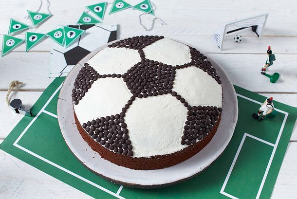 there is a cake decorated like a soccer ball on top of a green tablecloth