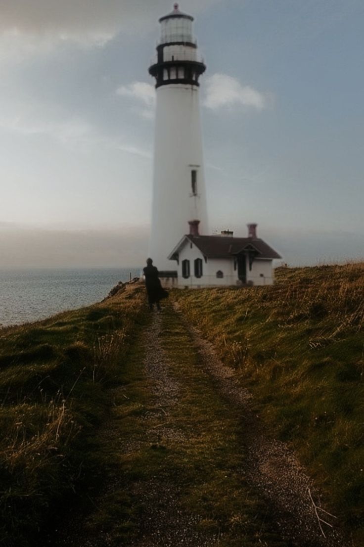 a person standing on top of a hill next to a light house