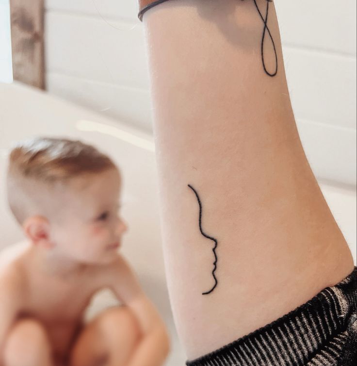 a woman with a tattoo on her arm next to a small child in the bathtub