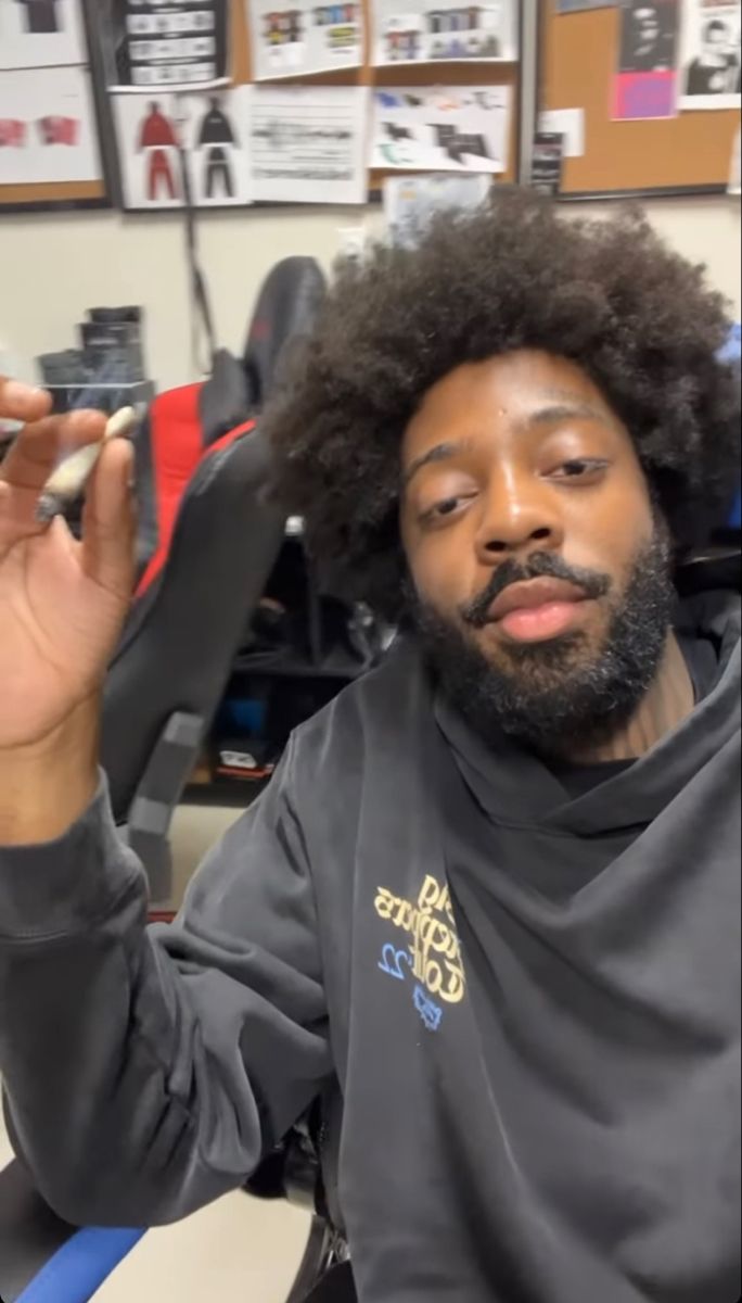 a man with an afro holding up a pair of scissors